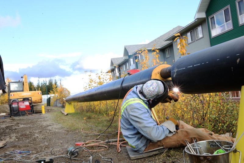 Welder working on pipe outdoors